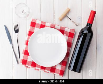 Table setting with empty plate, wine glass and red wine bottle Stock Photo