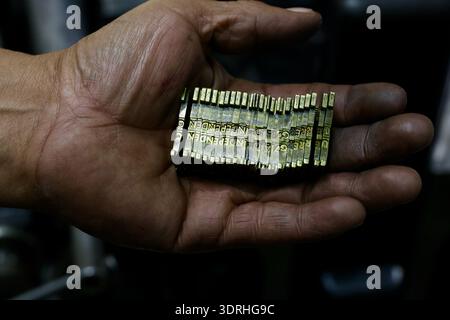 A print worker holds metal matrices used in a Linotype or Intertype machine in a traditional printing workshop in Mexico, where hot metal typesetting Stock Photo