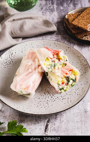 Spring rolls with crab meat, cucumber and herbs on a plate on the table vertical view Stock Photo