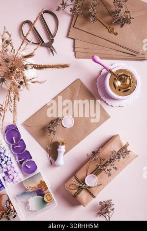 Craft envelope with wax seal and crafting items on pink top and vertical view Stock Photo