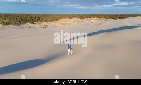 Walking on golden sand dunes in Denmark under a bright blue sky with gentle cloud patterns Stock Photo