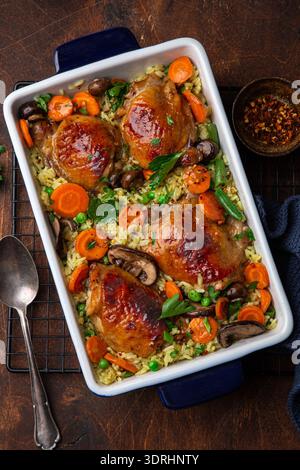 Oven baked chicken thighs with rice and vegetables on baking dish Stock Photo