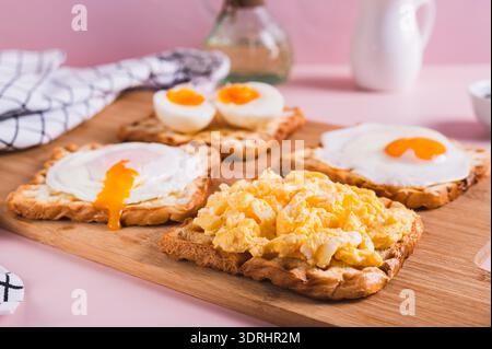Scrambled egg, poached egg, fried egg, boiled egg on toast on a board Stock Photo