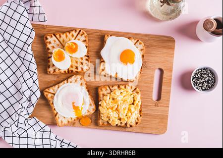 Scrambled egg, poached egg, fried egg, boiled egg on toast on a board top view Stock Photo