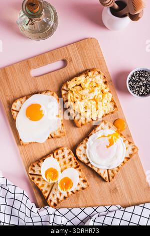 Eggs prepared to different recipes on toast on a wooden board top and vertical view Stock Photo