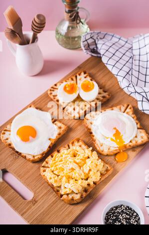 Eggs prepared to different recipes on toast on a wooden board vertical view Stock Photo