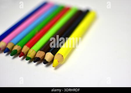Close-up of colorful wooden pencils arranged diagonally on white background with shallow depth of field. Creative art supplies concept, education, dra Stock Photo