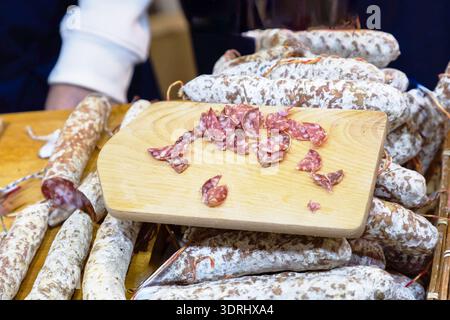 Some slices of traditional sausage salami fuet or dry sausage, covered with fermented mold on a wooden table. High quality sausa Stock Photo
