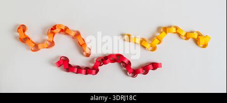 Three colored handmade paper chains on a light background top view Stock Photo