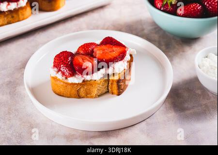 Sweet toast with ricotta and strawberry jam on a plate on the table Stock Photo