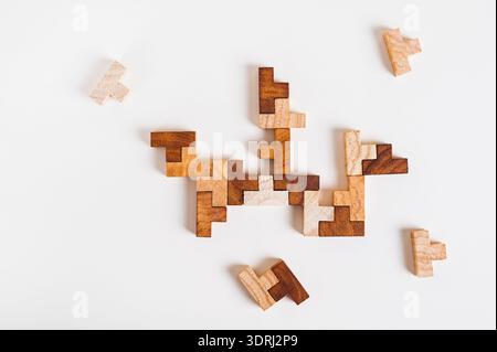 Wooden puzzle pieces stacked together on a light background top view Stock Photo
