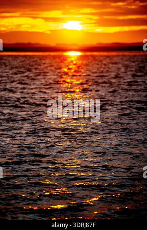 Blurred sunset or sunrise over the sea with small waves glittering in the sunlight Stock Photo