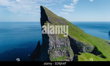 Majestic peak rises above the ocean in Faroe Islands under a clear blue sky Stock Photo