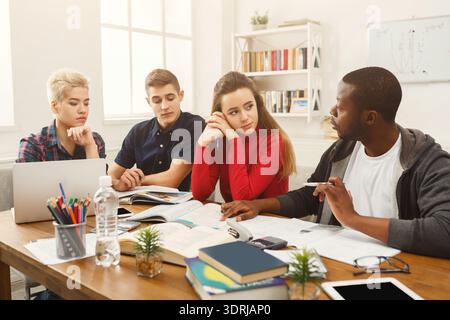 Students Engage in Group Discussion While Studying Together at a Shared Table in a Bright Room Stock Photo