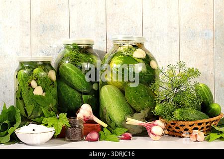 Homemade pickling recipe, cucumbers and pickling ingredients, Pickled cucumbers in jars with garlic and dill on wooden kitchen t Stock Photo