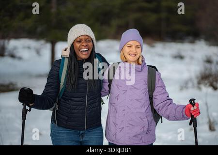 Diverse women friends enjoying winter hiking in snow Stock Photo
