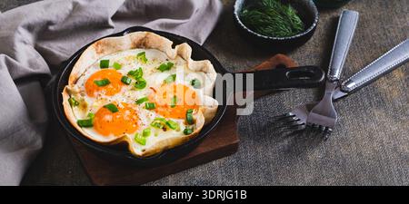 Homemade scrambled eggs in pita bread with herbs in a frying pan on the table web banner Stock Photo