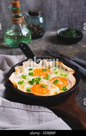 Homemade scrambled eggs in pita bread with herbs in a frying pan on the table vertical view Stock Photo