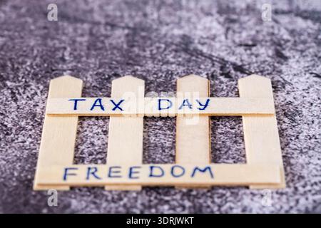 Tax day and freedom text handwritten on the beige wooden fence on grunge gray background. Stock Photo
