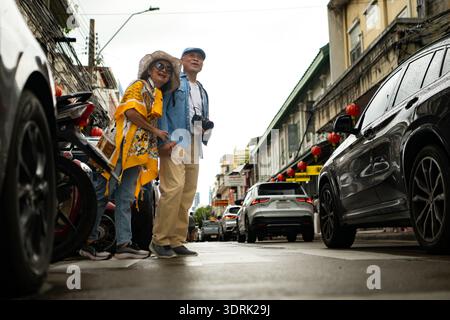 Happy senior couple walking on a city street, holding hands and sightseeing together Stock Photo