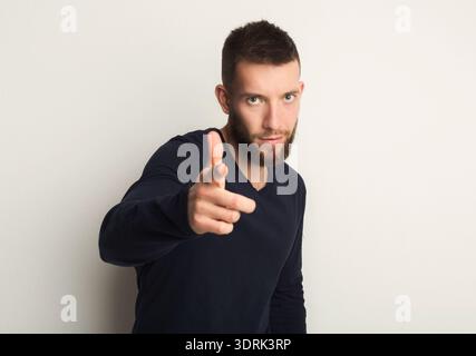 Man Points Finger While Posing Against Neutral Background in Studio Setting Stock Photo