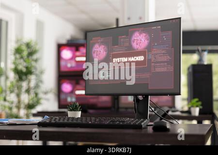 Empty office interior shows multiple monitors with hacked system warnings and security alerts. Technology concept illustrates cybercrime, compromised networks, and digital interface vulnerability. Stock Photo
