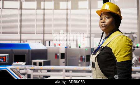 Engineer in smart factory overseeing robotic assembly lines, ensuring quality control in manufacturing process. Worker monitoring automated conveyor systems, doing maintenance, camera A Stock Photo