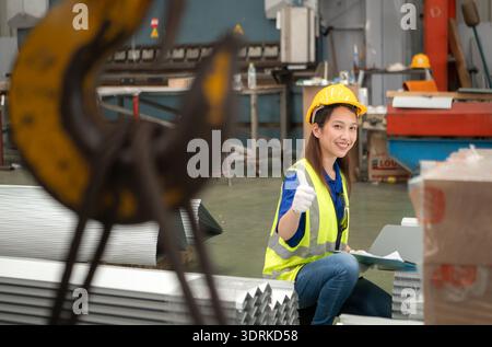 Young female workers are talking and inspecting steel plates for multipurpose forming Stock Photo