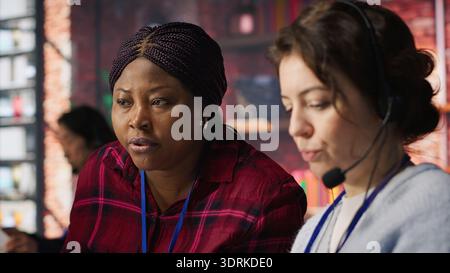 Account manager supervising work done by employee talking with customers to identify sales opportunities. Supervisor overseeing agent in office bonding with client to generate leads, camera A Stock Photo