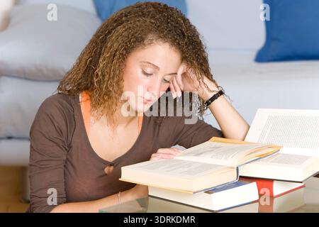 Young woman sitting at a table reading a book Stock Photo