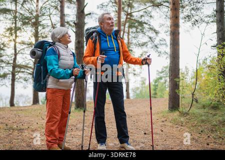 Hiking tourism adventure. Senior couple man woman enjoying outdoor recreation hiking in forest, Happy old people backpackers hik Stock Photo