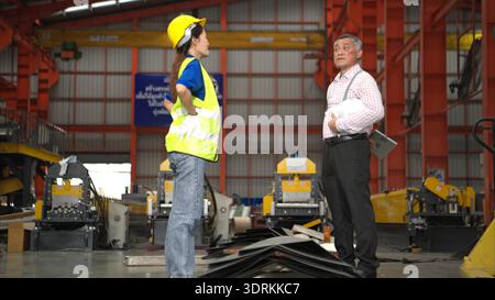 Senior engineers and young female workers are talking and inspecting steel plates Stock Photo