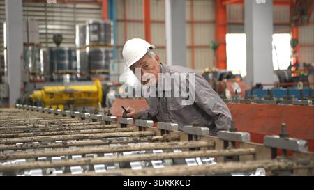 Senior experienced technician checking large machine on a production line Stock Photo