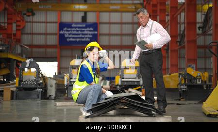 Senior engineers and young female workers are talking and inspecting steel plates Stock Photo