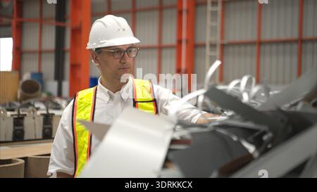 Industrial worker inspecting inside a large metal tube in a factory wearing safety helmet Stock Photo