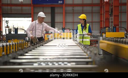 Senior engineers and young female workers are talking and inspecting machines on a production line Stock Photo