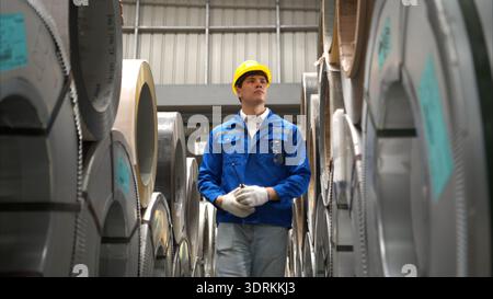 Industrial worker inspecting inside a large metal tube in a factory Stock Photo