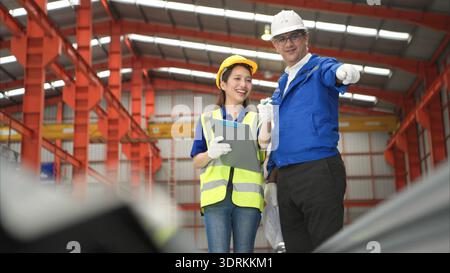Senior engineers and young female workers are talking and inspecting steel plates Stock Photo