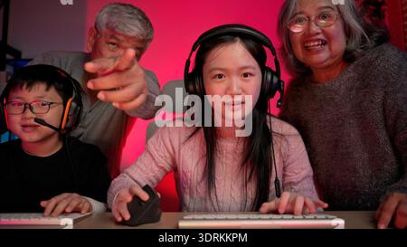 Happy grandparents playing games with grandchildren in in a neon lit room Stock Photo