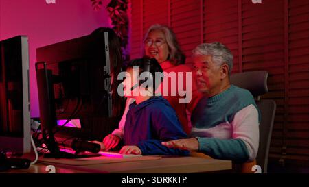 Happy grandparents playing games with grandchildren in in a neon lit room Stock Photo
