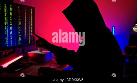 An expert hacker is decrypting data while hiding their face Stock Photo