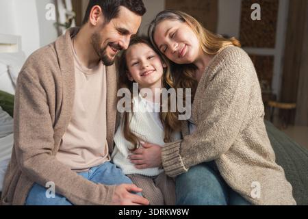 Happy family at home. Mother father children daughter relaxing on sofa indoor. Mom dad parents kid girl relax playing hugging ha Stock Photo