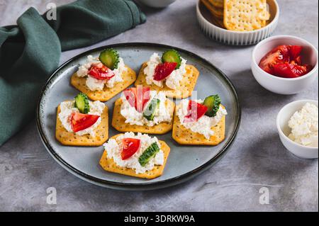 Cottage cheese and vegetables on crackers on a plate on the table Stock Photo