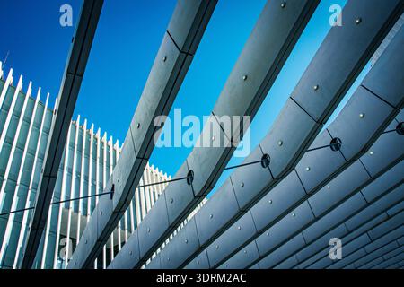 Dynamic view of contemporary architecture, featuring sweeping concrete beams and steel supports set against a vivid blue sky. Lisbon. Stock Photo