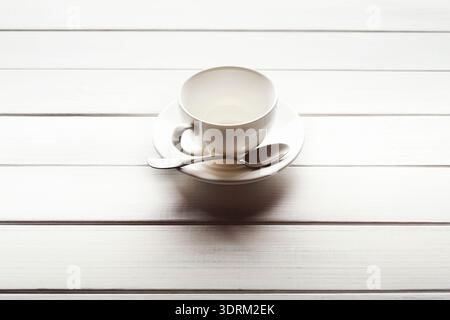 Empty Cup and Saucer Placed on Wooden Table, With Spoon Resting Beside in a Simple Setting Stock Photo