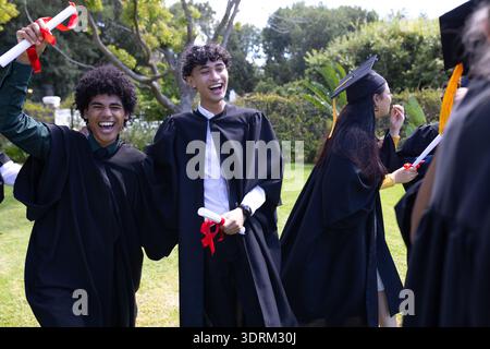 Celebrating outdoors, graduating students holding diplomas and smiling joyfully. Graduation, achievement, celebration, accomplis Stock Photo