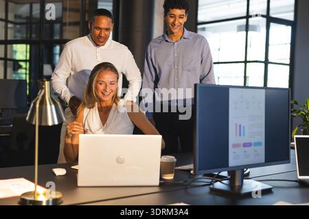Business professionals collaborating on laptop in modern office, smiling and engaged. Teamwork, collaboration, successful, corpo Stock Photo