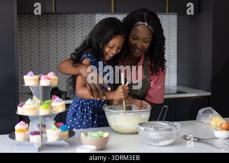 Baking cupcakes, mother and child sharing joyful moment in modern kitchen together. Family, bonding, cooking, homemade, dessert, Stock Photo