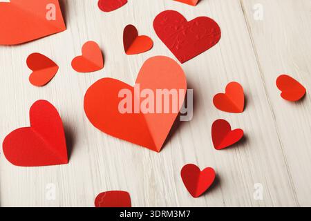 Collection of Red and Pink Paper Hearts Arranged on a Light Wooden Surface for Decoration Stock Photo