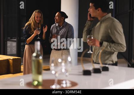 Gathering in modern office, colleagues having drinks and conversation in evening. Coworkers, networking, casual, teamwork, colla Stock Photo